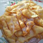 Filhoses tradicionais douradas, polvilhadas com açúcar e canela.